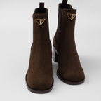 Suede booties – the enameled metal triangle logo embellishes the style with its sleek, distinctive – LUX VERSE Luxury Designer Fashion Outlet